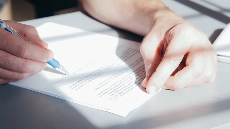 Hands writing notes on a sheet of paper in sunlight