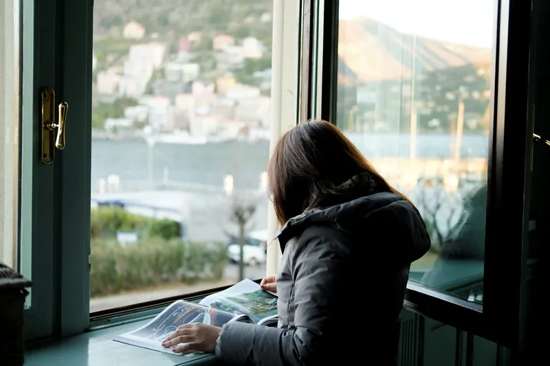 A person reading by an open window above a harbour